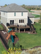Light brown second story deck with stairs and black railing