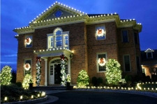 Brick house trimmed with yellow lights and wreaths in windows