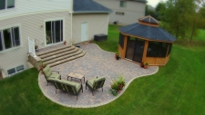 Organic shaped tan and grey brick backyard patio with gazebo